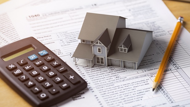 A tiny house on pieces of paper next to a pencil and calculator