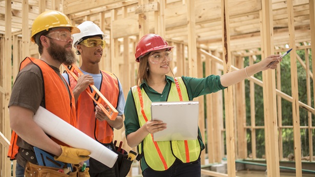 Woman construction worker explaining to two male workers on job site