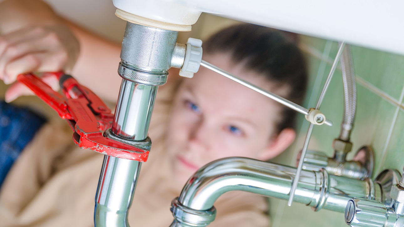 Woman using a wrench to tighten a pipe