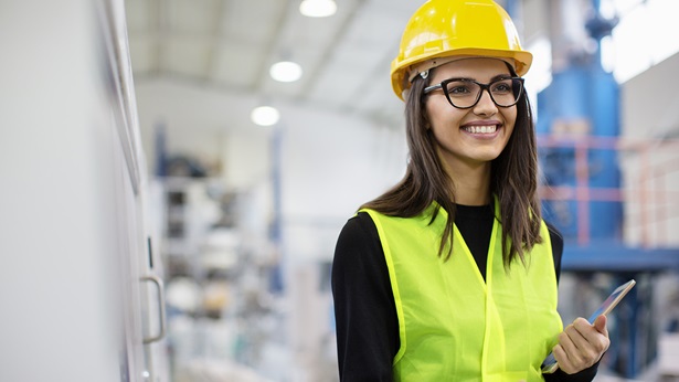 Young woman wearing a hard hat and vest on site