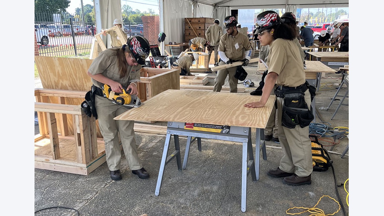 two female carpentry students cut lumber
