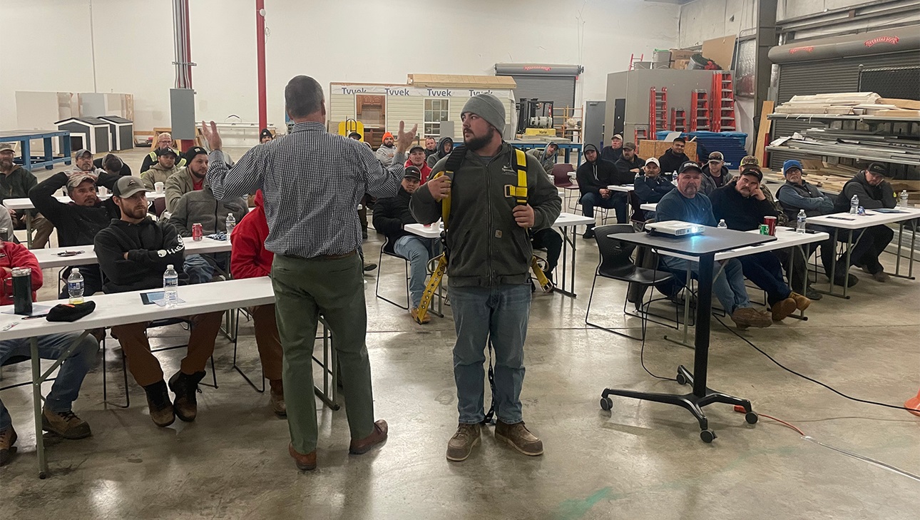 Volunteer helps demonstrate harness use at fall prevention training