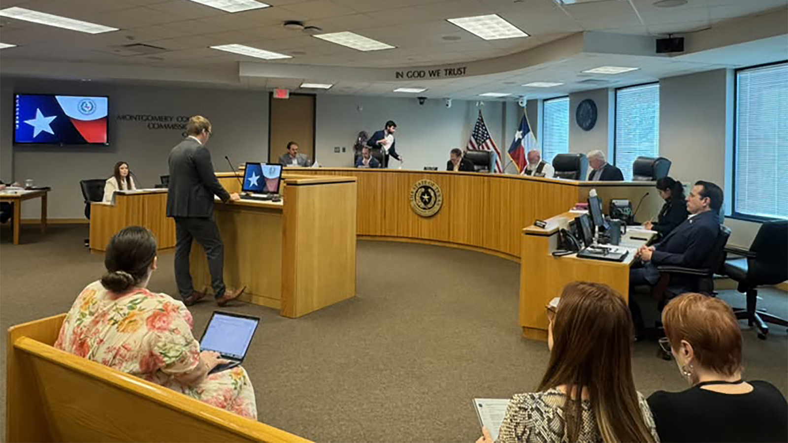man standing at podium in front of panel in a meeting