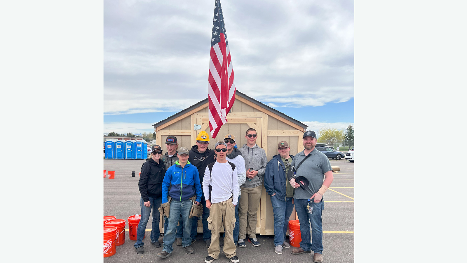 students standing in front of shed with American flag