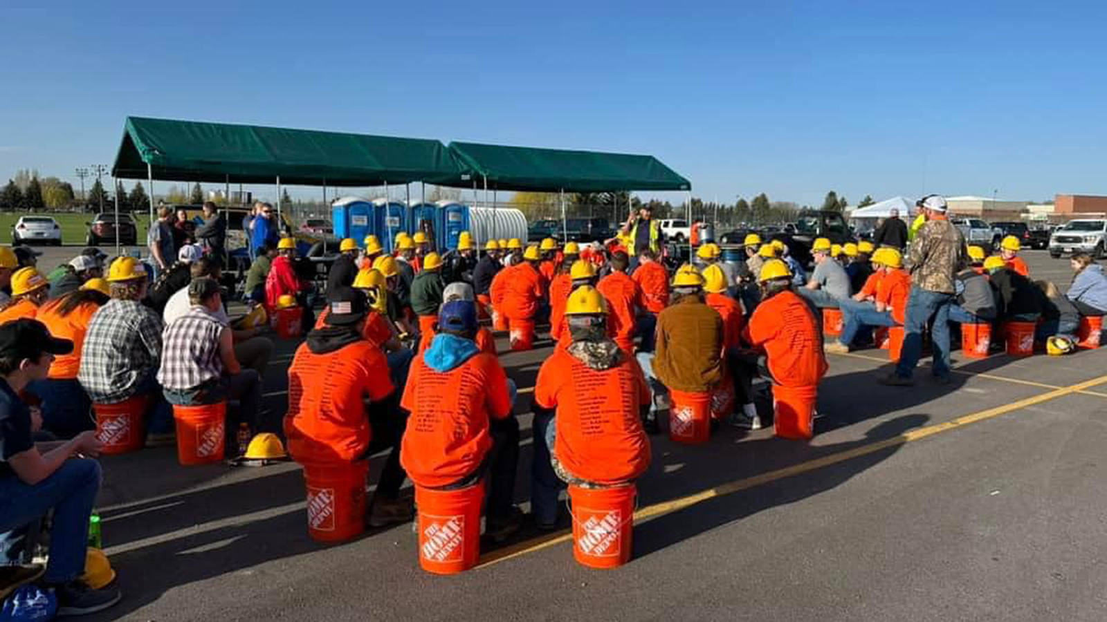 a group of students sitting on painters buckets listening to presentation