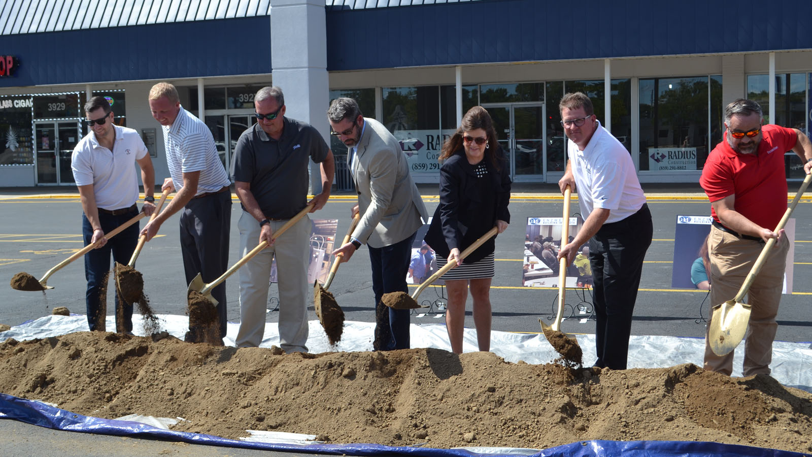 individuals lined up with shovels with dirt 