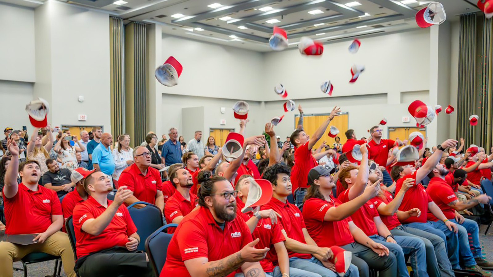 Students throw hats in the air at the NEFBA apprenticeship graduation.