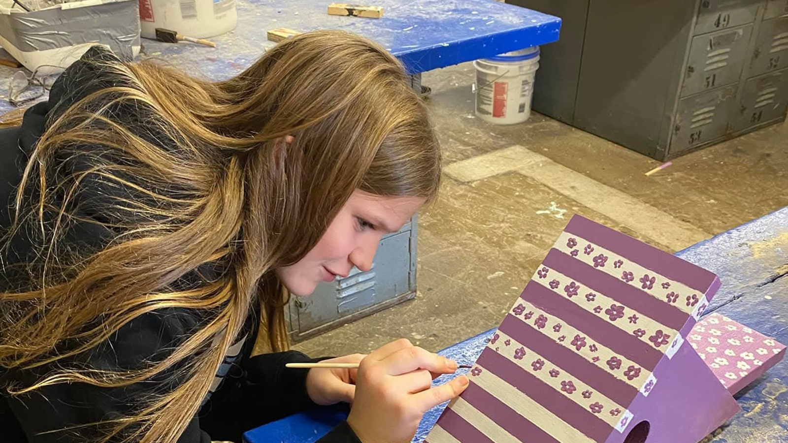 A student paints a birdhouse as part of local workforce development training.