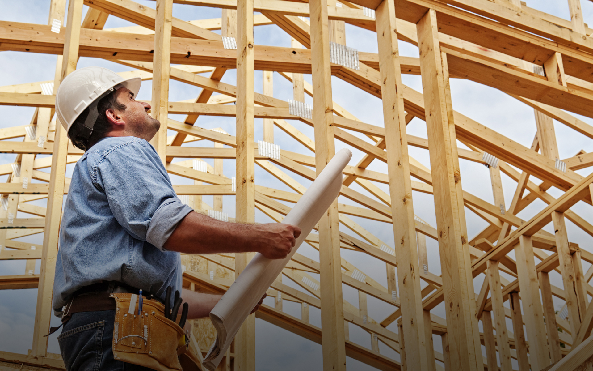 A construction worker next to a frame of a house