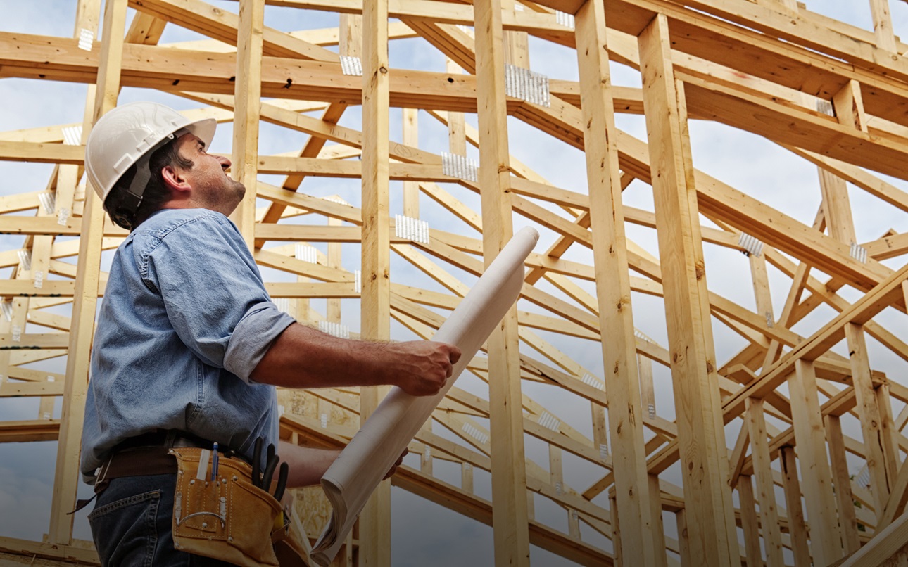 A construction worker next to a frame of a house