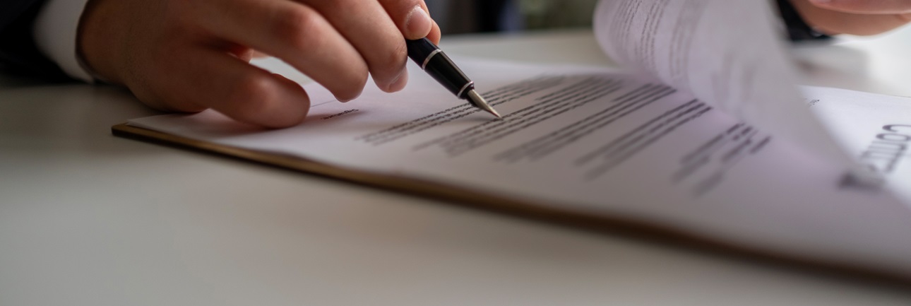 Man holding pen reading through documents