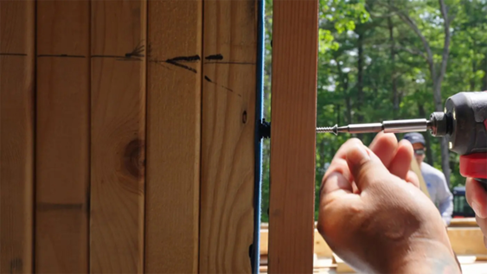 Close-up of a worker adjusting a door frame with a drill during installation.