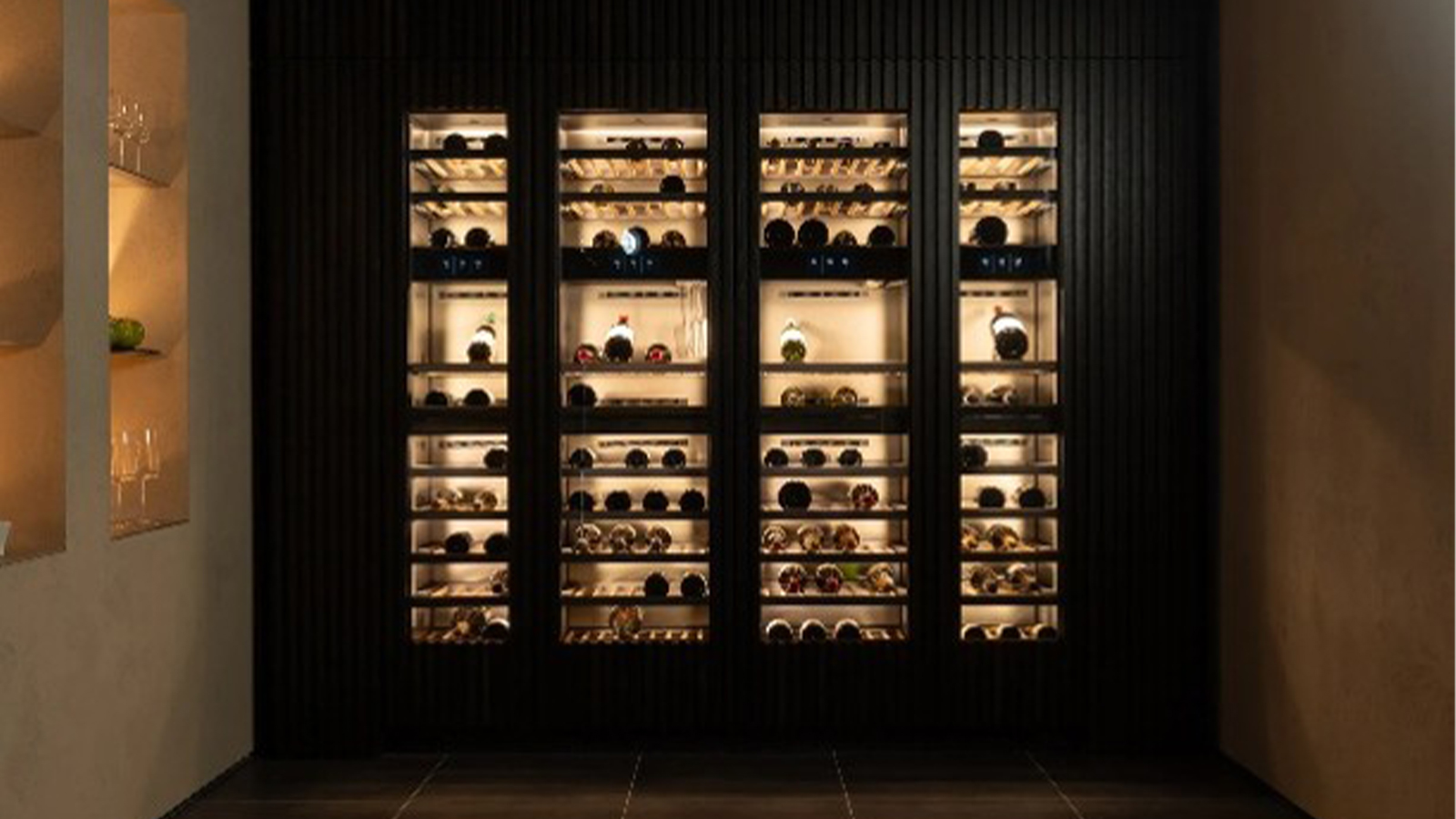 Illuminated built-in wine storage with glass-front cabinets.