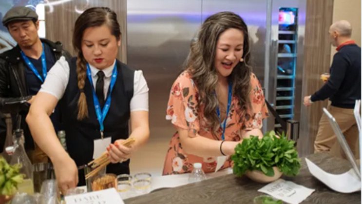 Two women at a counter arranging food trays