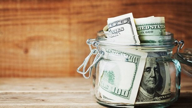 A jar with dollar bills on a wood counter