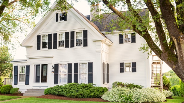 A large white single family home surrounded by trees