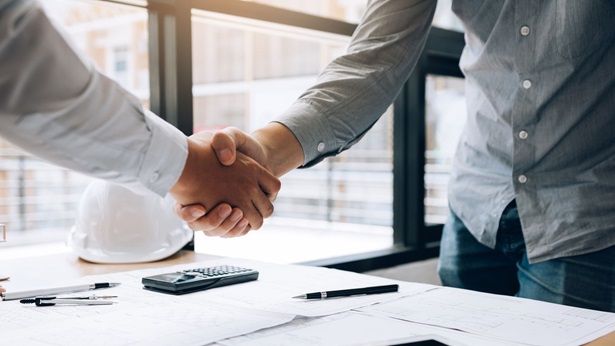 Two men shaking hands over a desk