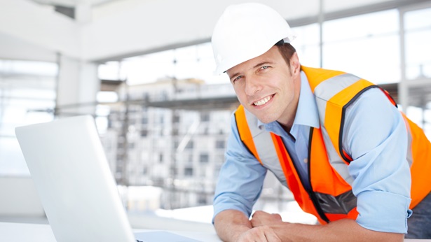 Construction man smiling in front of laptop